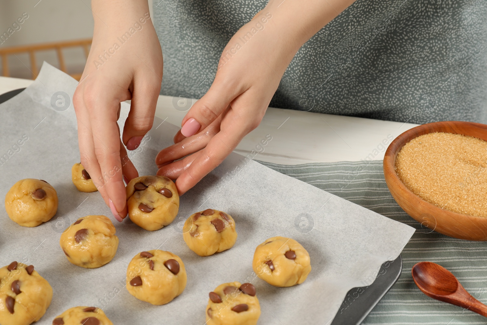 Photo of Woman preparing chocolate chip cookies at white table in kitchen, closeup