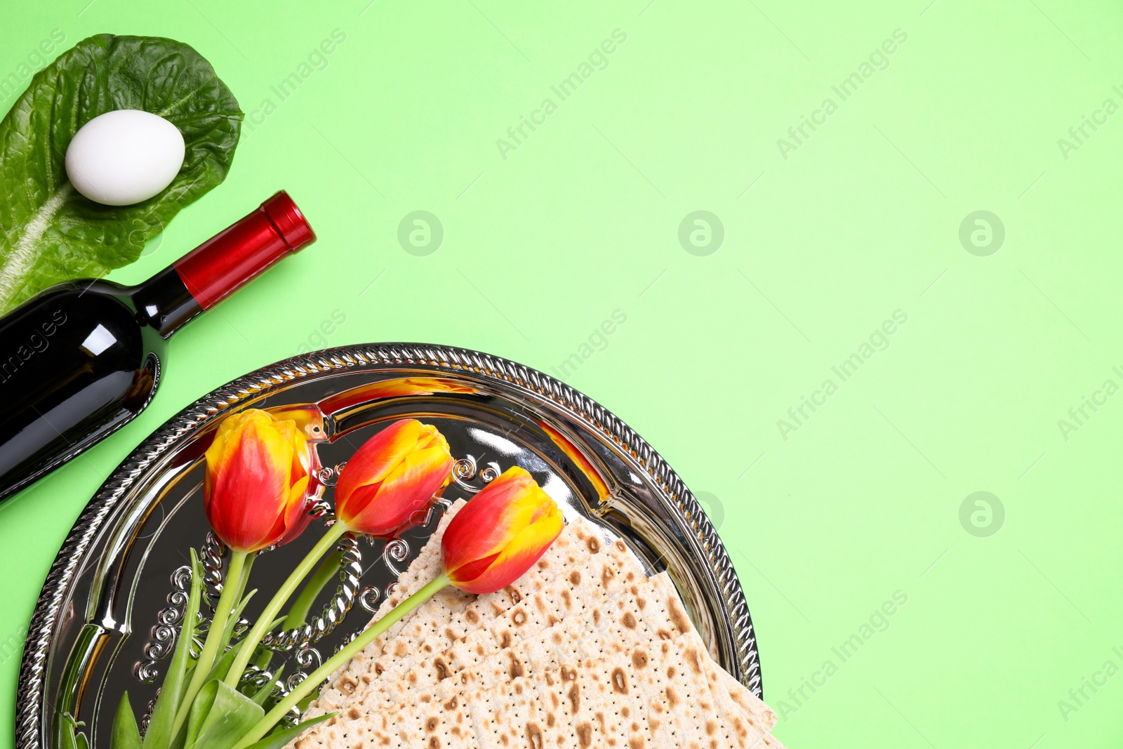 Photo of Flat lay composition with symbolic Pesach (Passover Seder) items on green background, space for text