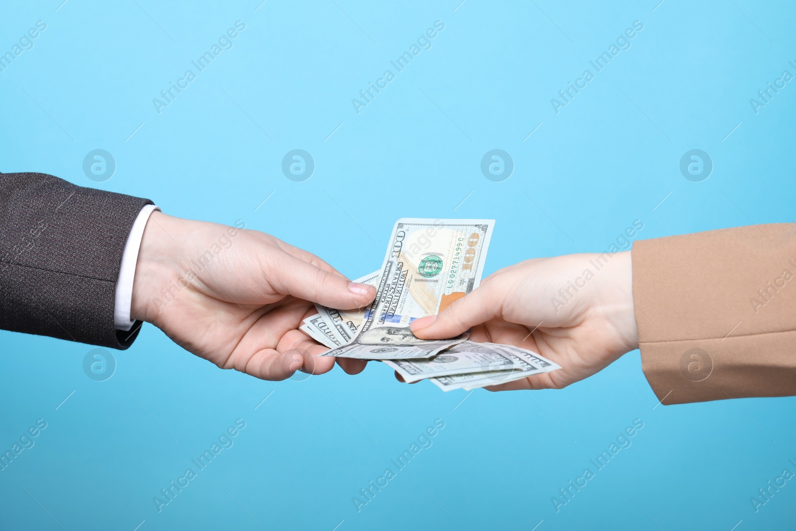 Photo of Man giving money to woman on light blue background, closeup. Currency exchange