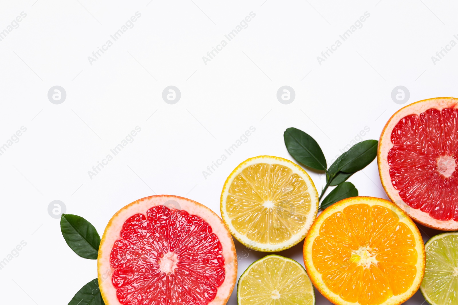 Photo of Different cut citrus fruits and leaves on white table, flat lay. Space for text