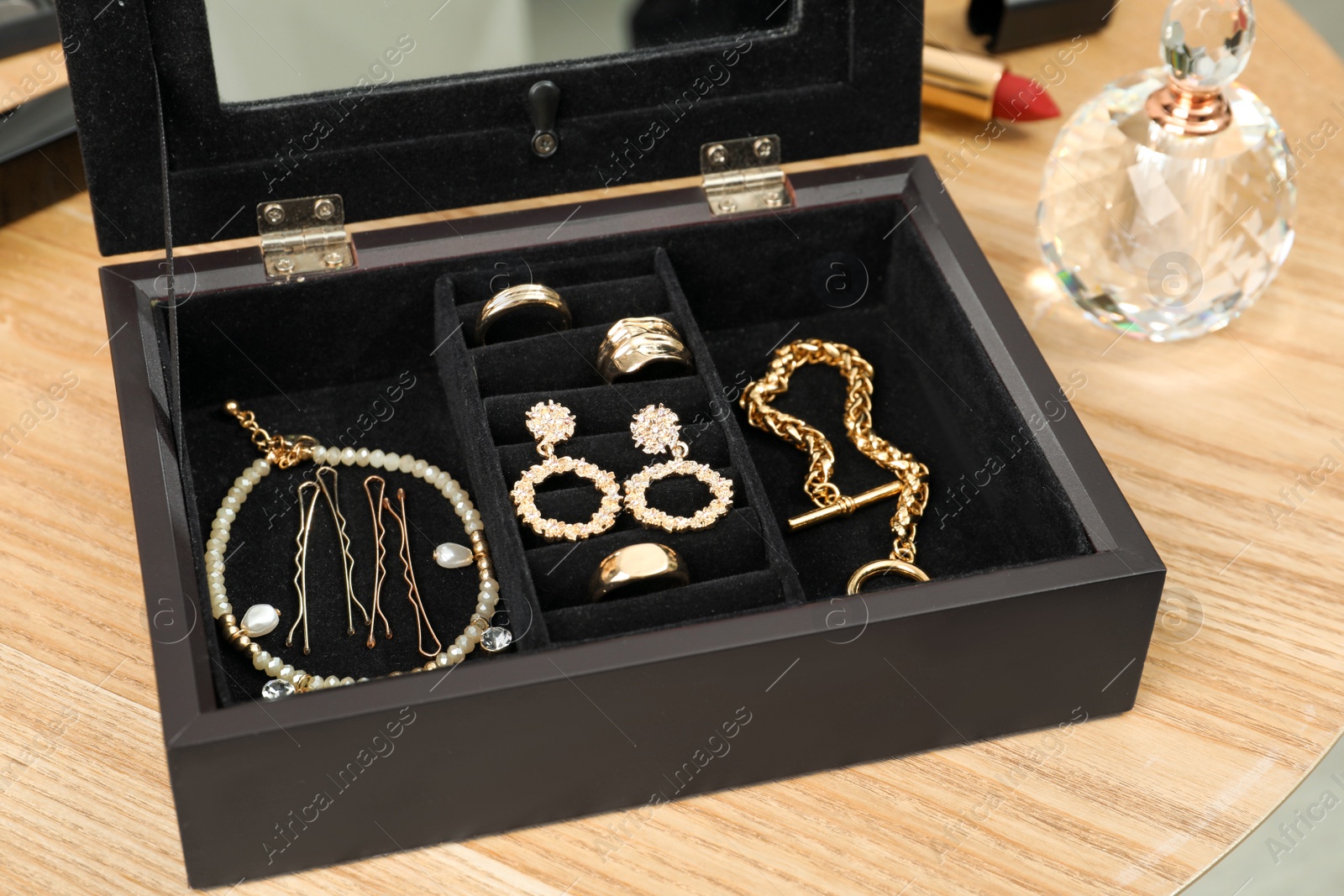 Photo of Jewelry box with stylish golden bijouterie on wooden table, closeup