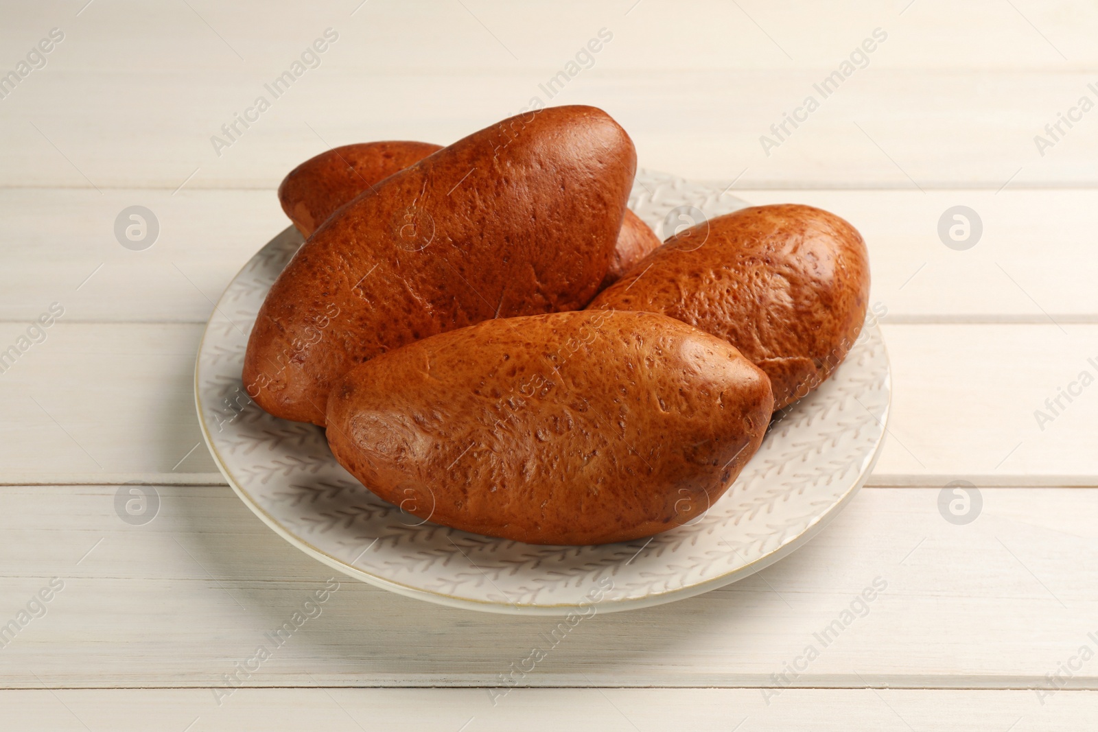 Photo of Delicious baked patties on white wooden table