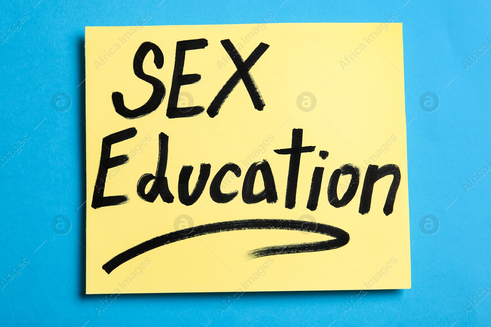 Photo of Note with phrase "SEX EDUCATION" on blue background, top view