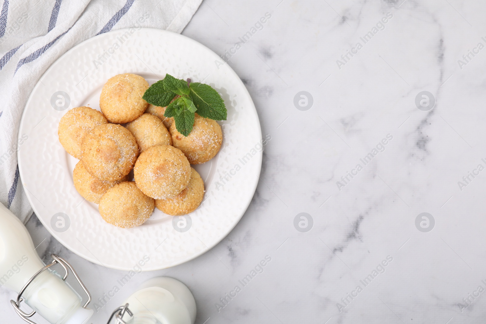 Photo of Tasty sweet sugar cookies, milk and mint on white marble table, top view. Space for text