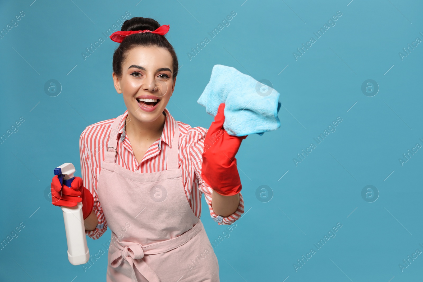 Photo of Young housewife with detergent and rug on light blue background, space for text