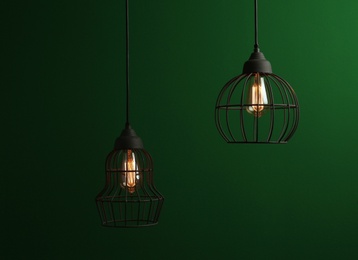 Hanging lamp bulbs in chandeliers against green background