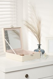 Photo of Jewelry box with accessories, perfumes and decor on white wooden table indoors
