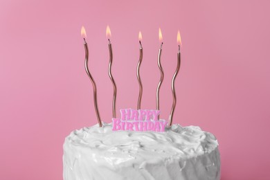 Delicious cake with cream and burning candles on pink background, closeup
