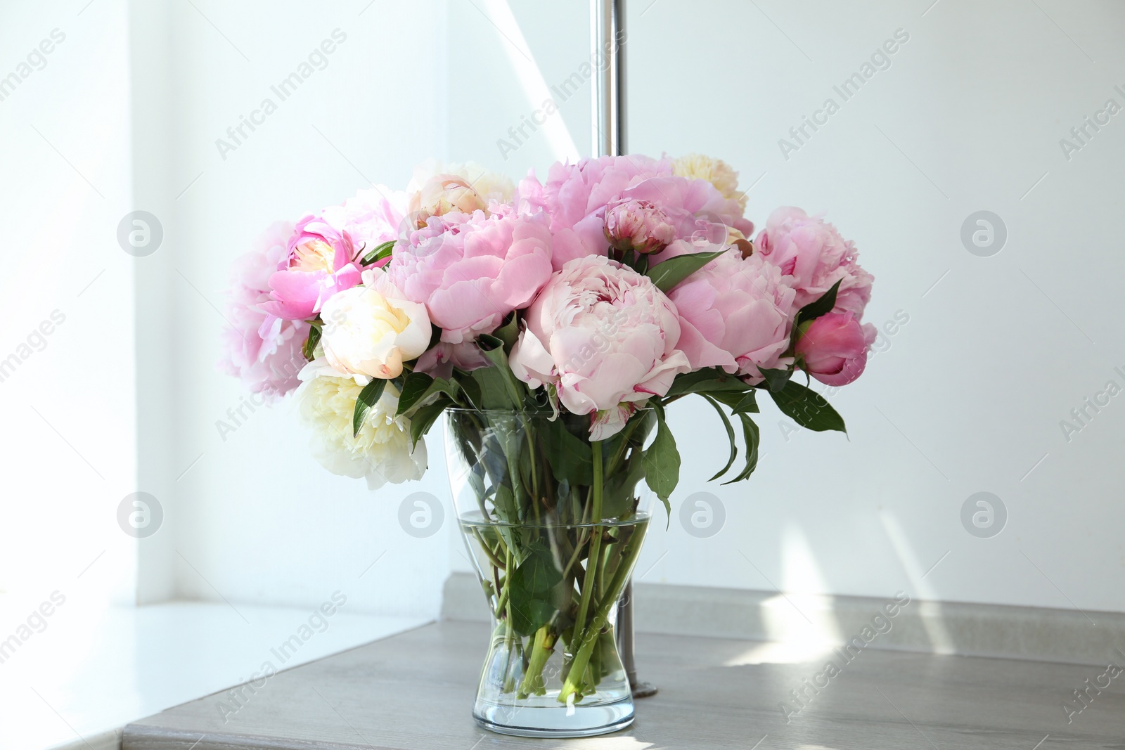 Photo of Bouquet of beautiful peonies in vase on wooden table