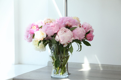 Photo of Bouquet of beautiful peonies in vase on wooden table