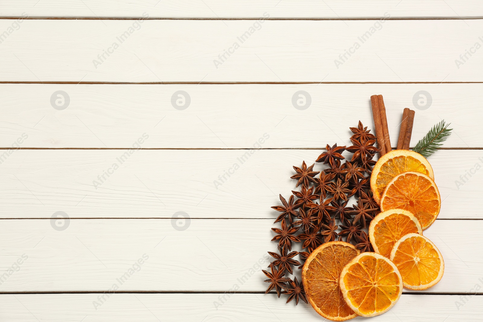 Photo of Flat lay composition with dry orange slices, anise stars and cinnamon sticks on white wooden table. Space for text