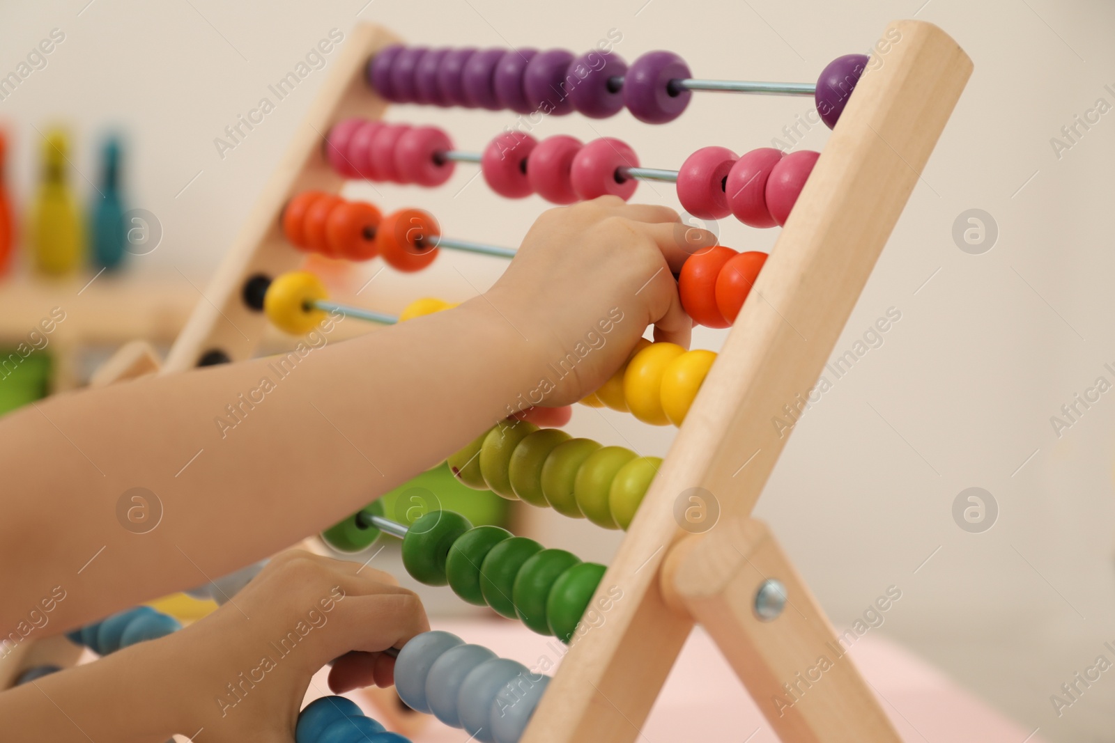 Photo of Cute child playing with wooden abacus at table in room, closeup