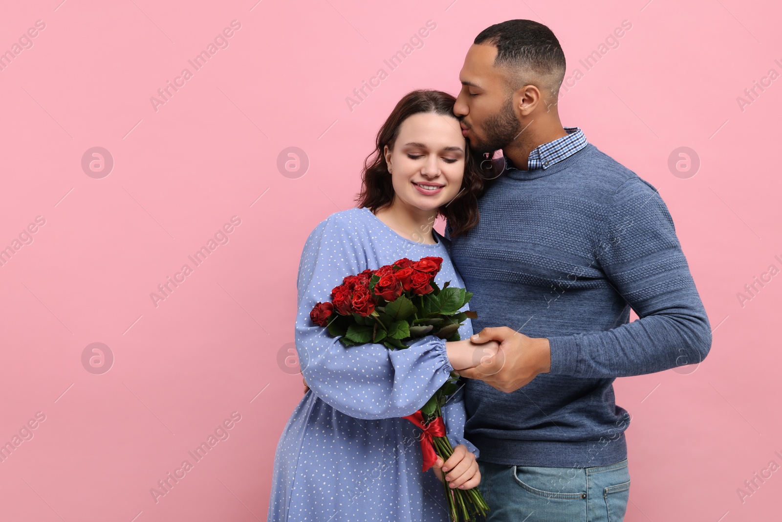 Photo of Happy couple celebrating Valentine's day. Beloved woman with bouquet of roses on red background, space for text