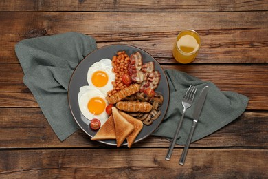 Photo of Plate with fried eggs, sausages, mushrooms, beans, bacon and toasted bread on wooden table, flat lay. Traditional English breakfast