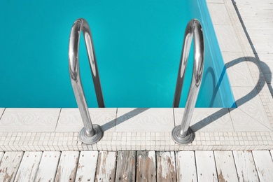 Modern swimming pool with ladder at resort