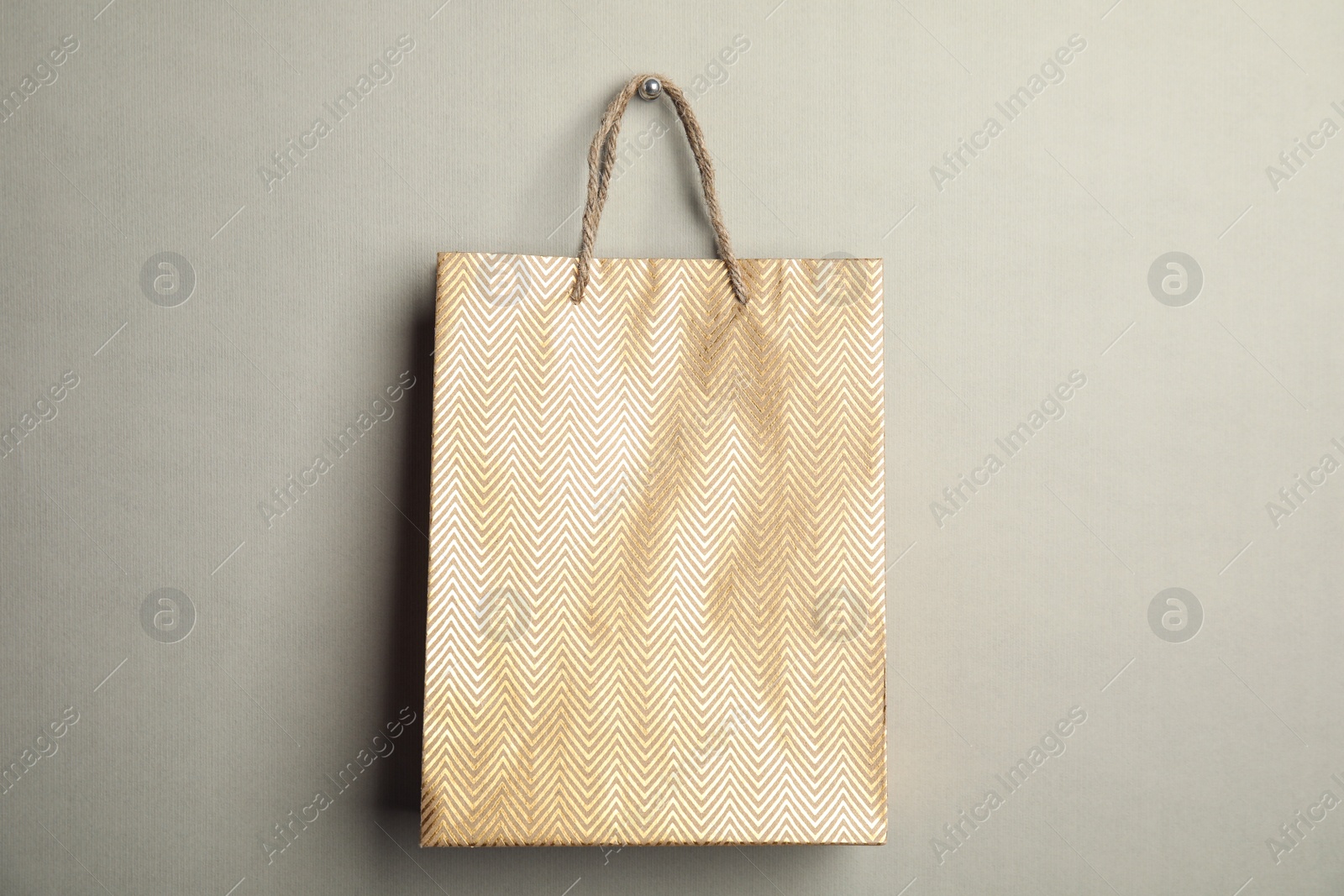 Photo of Gold shopping paper bag on grey background