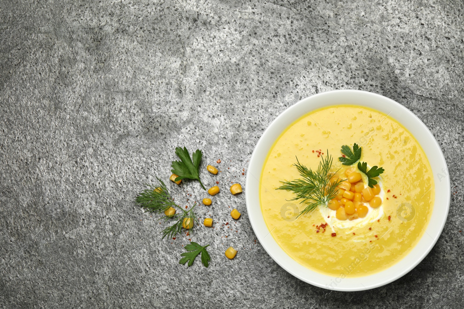 Photo of Delicious creamy corn soup served on grey table, flat lay. Space for text