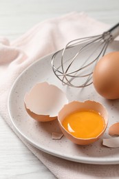 Whole and cracked chicken eggs on white wooden table, closeup