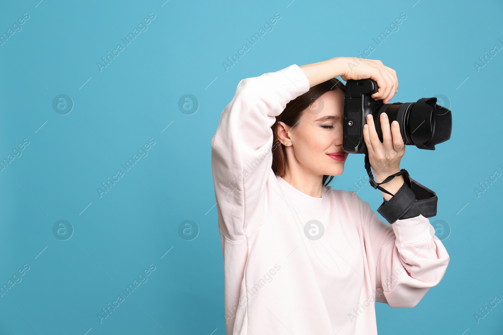 Photo of Professional photographer taking picture on light blue background. Space for text