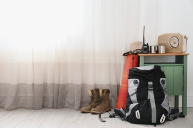 Photo of Set of camping equipment on floor near window. Space for text