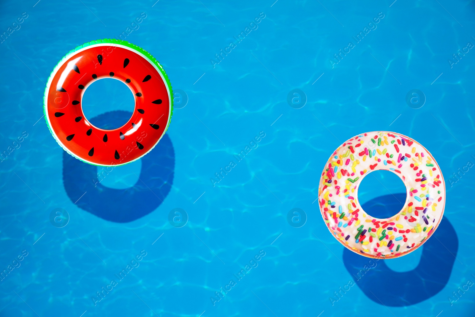 Image of Different inflatable rings floating in swimming pool, top view