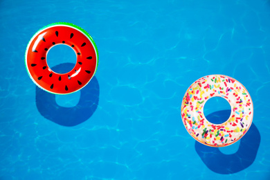 Image of Different inflatable rings floating in swimming pool, top view