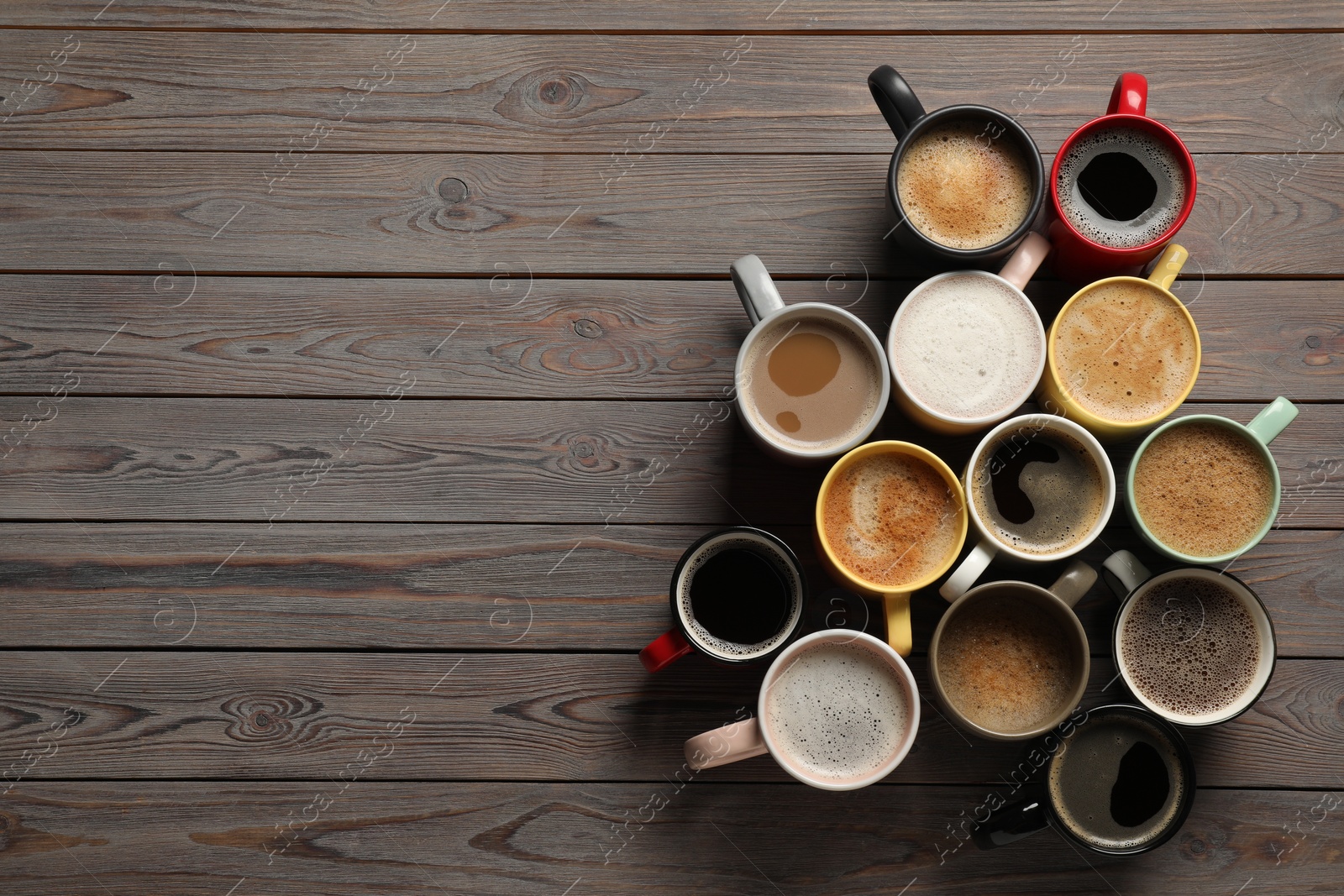 Photo of Many different cups with aromatic coffee on wooden table, flat lay. Space for text