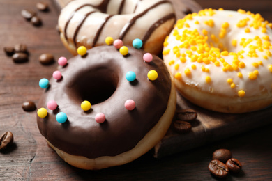 Photo of Yummy donuts with colorful sprinkles on wooden table, closeup