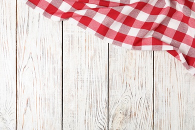 Photo of Checkered picnic blanket on wooden background, top view. Space for text