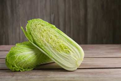 Photo of Whole and cut fresh ripe Chinese cabbages on wooden table, space for text