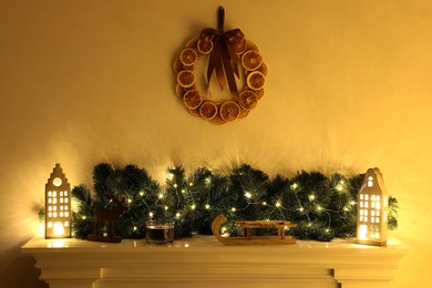 Fireplace with Christmas accessories and decorative wreath on white wall
