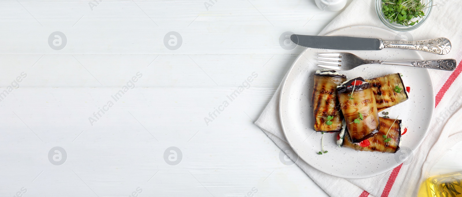 Image of Delicious baked eggplant rolls served on white wooden table, flat lay with space for text. Banner design