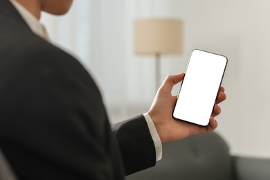 Photo of Man using smartphone with blank screen indoors, closeup. Mockup for design