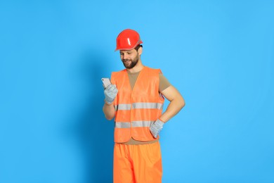 Man in reflective uniform with smartphone on light blue background