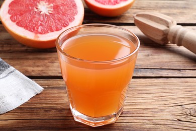 Photo of Tasty freshly made grapefruit juice on wooden table