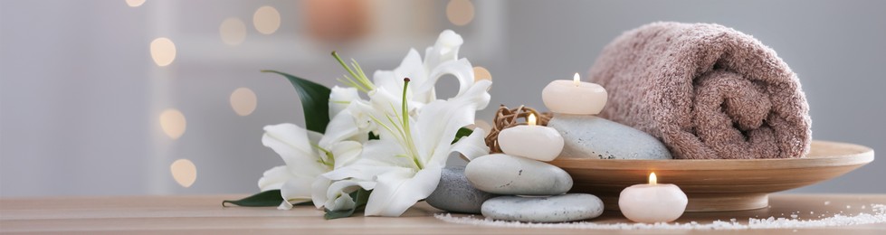 Image of Candles, hot stones, towel and flowers on table in spa cabinet, closeup. Banner design with space for text