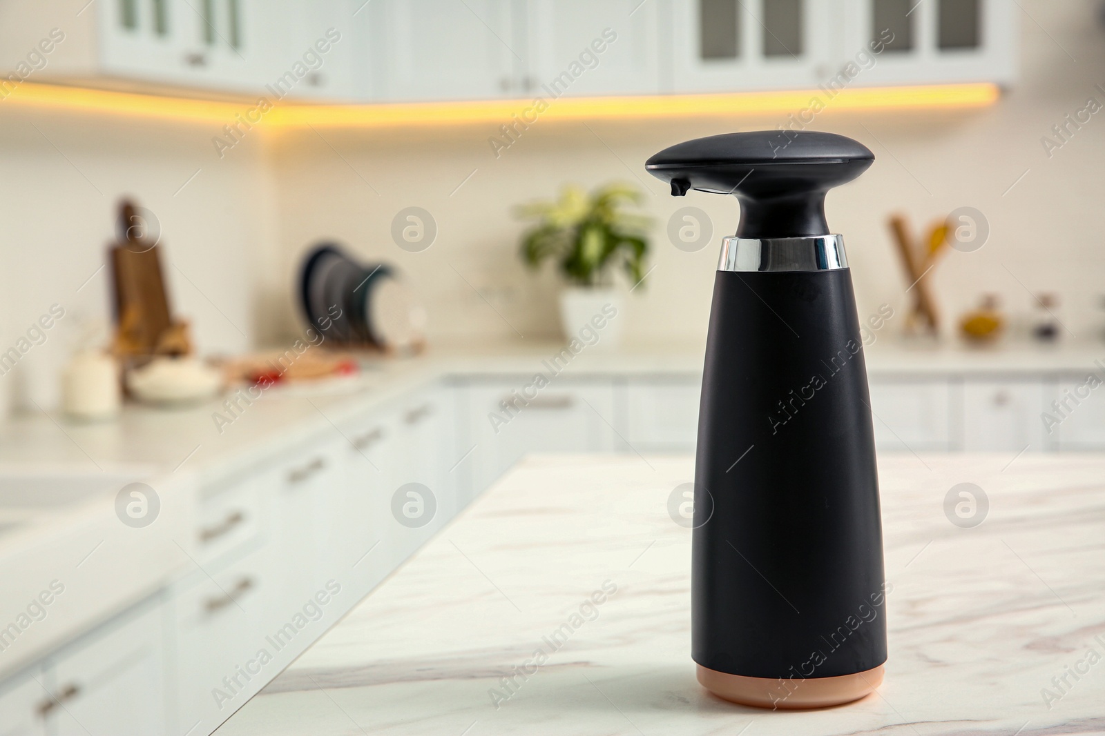 Photo of Modern automatic soap dispenser on countertop in kitchen. Space for text