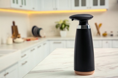 Modern automatic soap dispenser on countertop in kitchen. Space for text