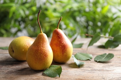 Ripe pears on wooden table against blurred background. Space for text