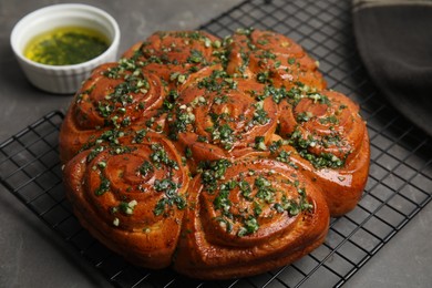 Photo of Traditional Ukrainian garlic bread with herbs (Pampushky) and aromatic oil on grey table, closeup