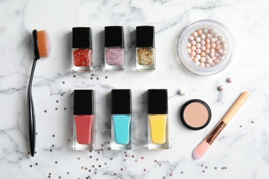 Photo of Flat lay composition with bottles of nail polish and different cosmetics on marble background
