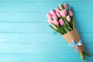 Beautiful pink spring tulips on light blue wooden background, top view. Space for text