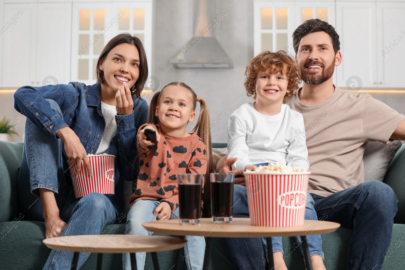 Photo of Happy family watching TV with popcorn on sofa at home