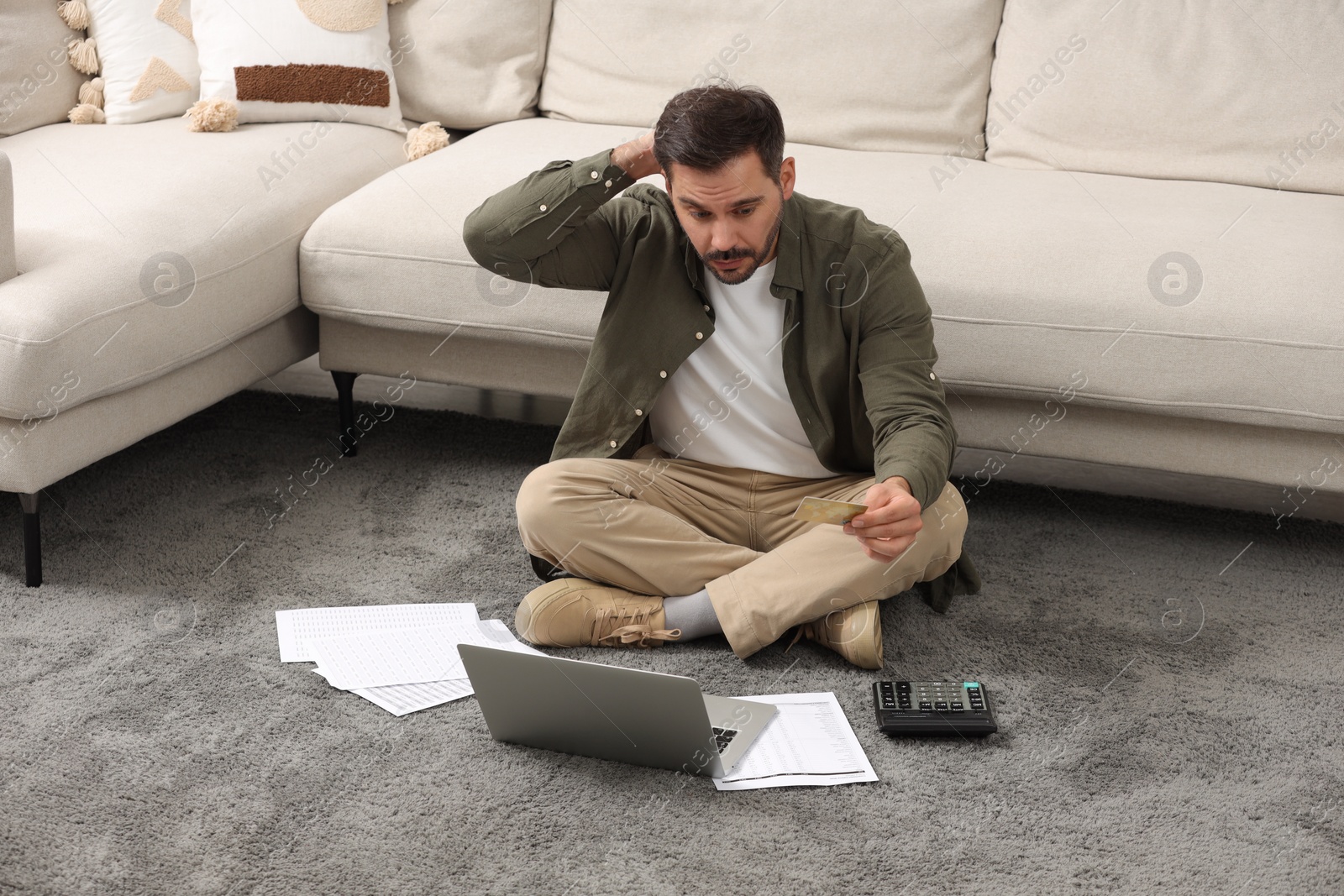 Photo of Confused man with laptop, debt notifications and credit card planning budget at home. Financial problem