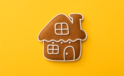 Photo of Christmas house shaped gingerbread cookie on yellow background, top view