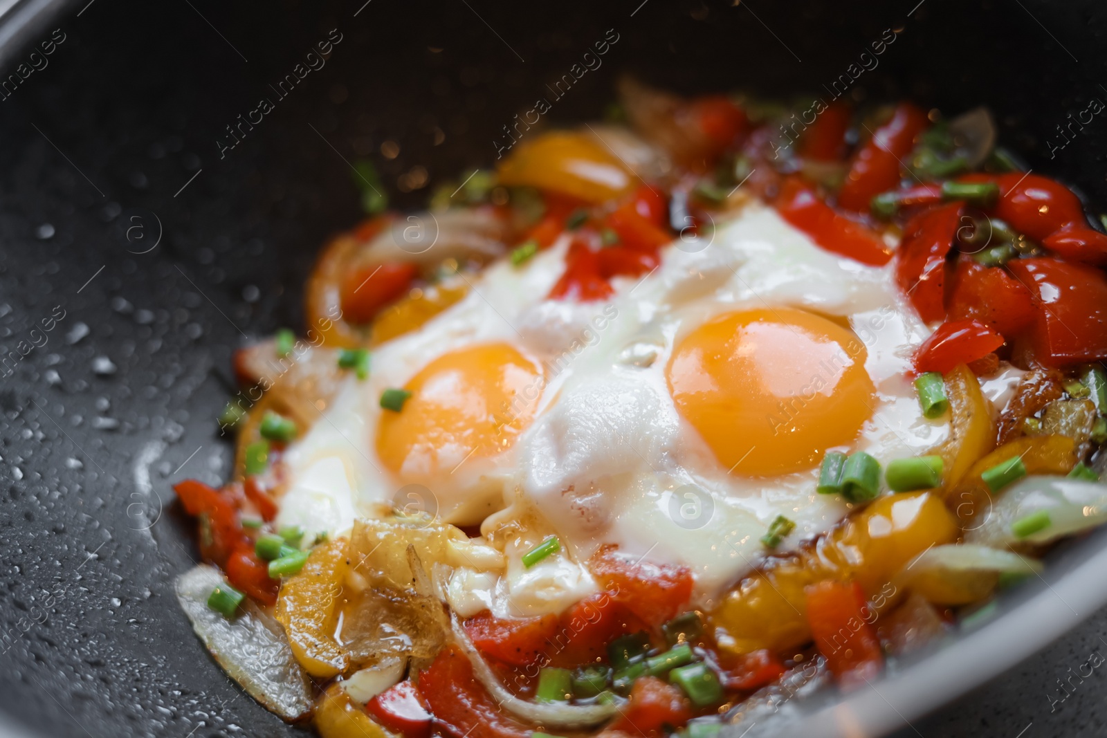 Photo of Cooking tasty eggs with vegetables in frying pan, closeup