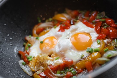 Cooking tasty eggs with vegetables in frying pan, closeup