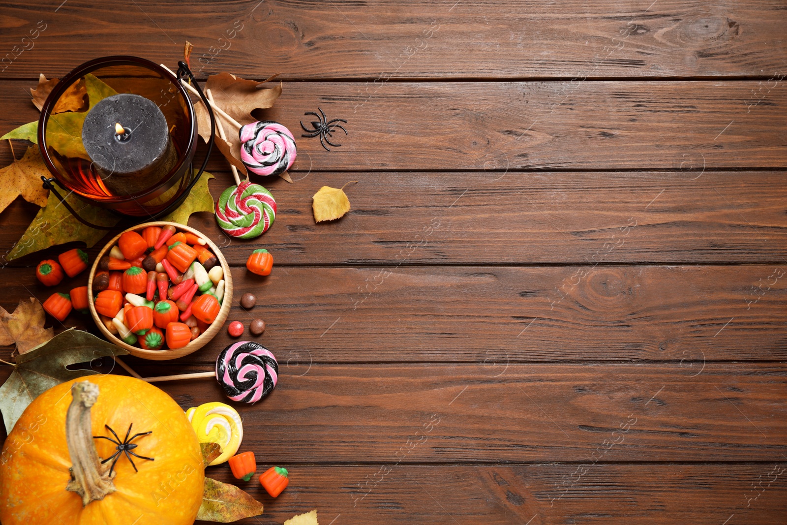 Photo of Flat lay composition with pumpkin head Jack lantern and Halloween treats on wooden background. Space for text