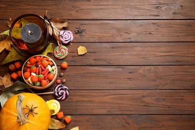 Flat lay composition with pumpkin head Jack lantern and Halloween treats on wooden background. Space for text