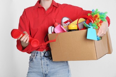 Photo of Woman holding box of unwanted stuff on white background, closeup